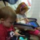 two small children on page watching ipads